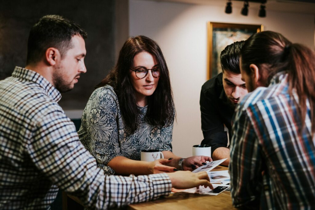 four people picking from a pile of images on a table