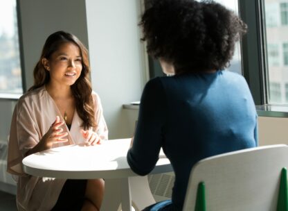 two professional women talking across a table