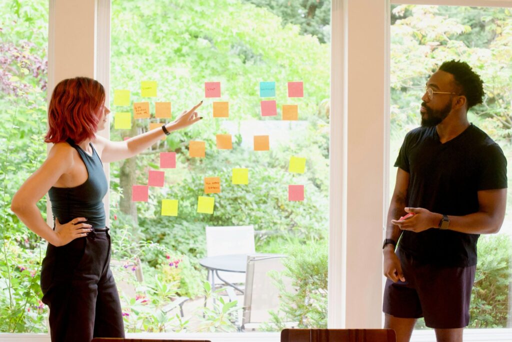 a woman pointing to sticky notes arranged on a window