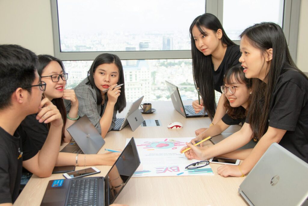 a group of colleagues around a table with computers and notes