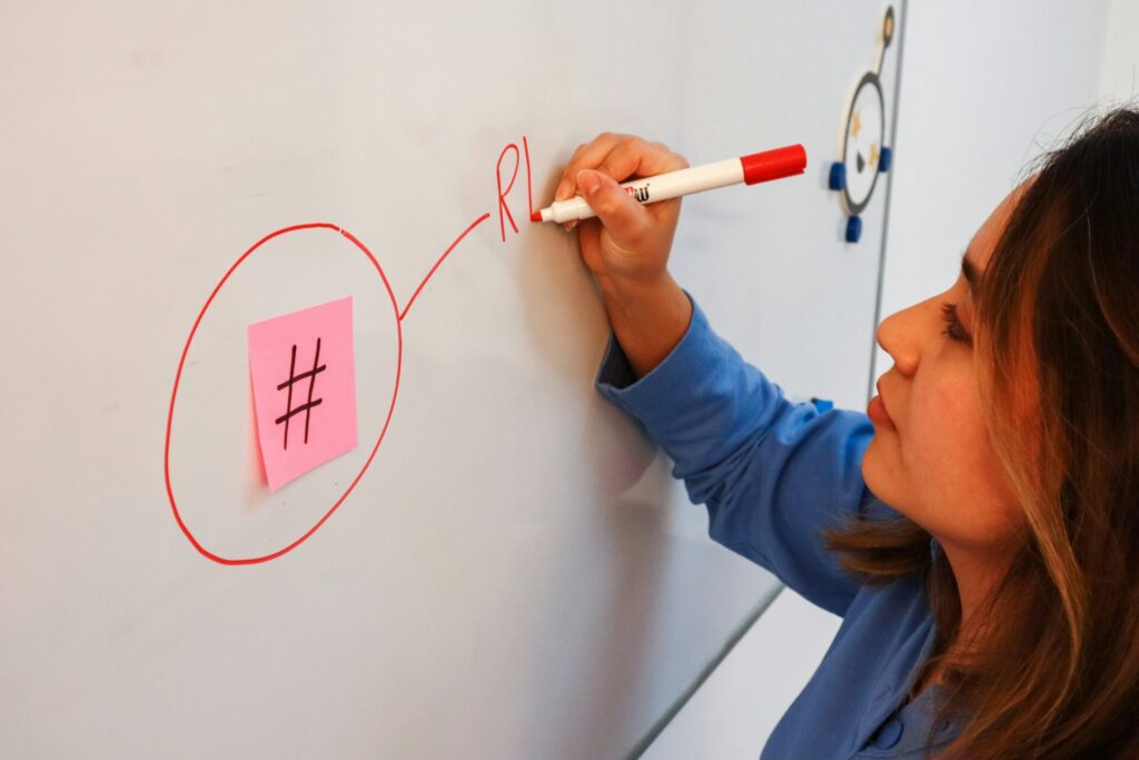 a woman writing on a whiteboard with a sharpie pen