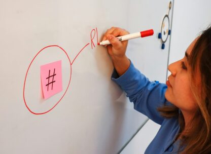 a woman writing on a whiteboard with a sharpie pen